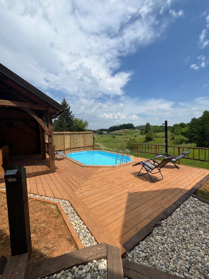 Pool and loungers on the wooden deck with views over the hills